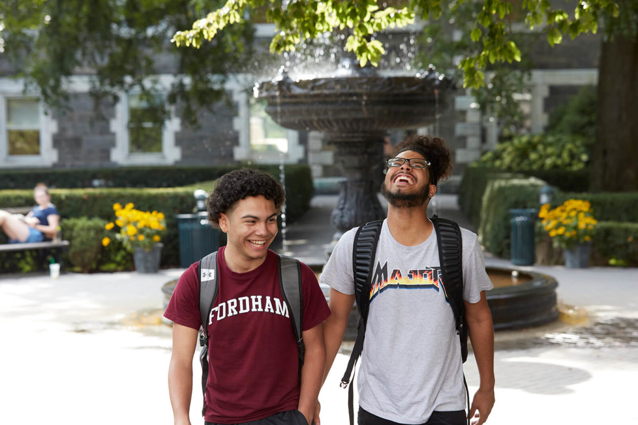 Students walking on campus in front of a large water fountain.