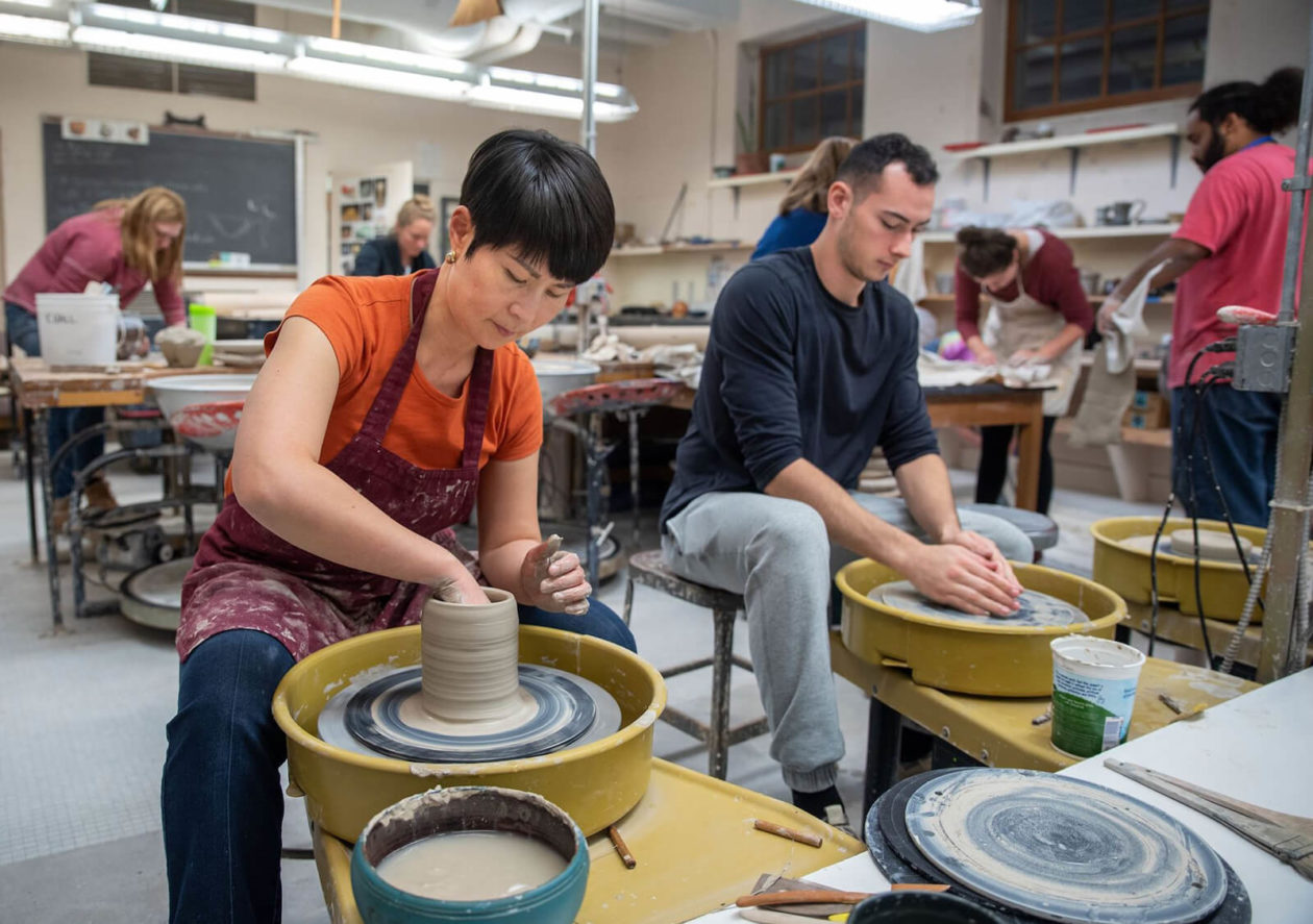 Students spinning pottery in a classroom.