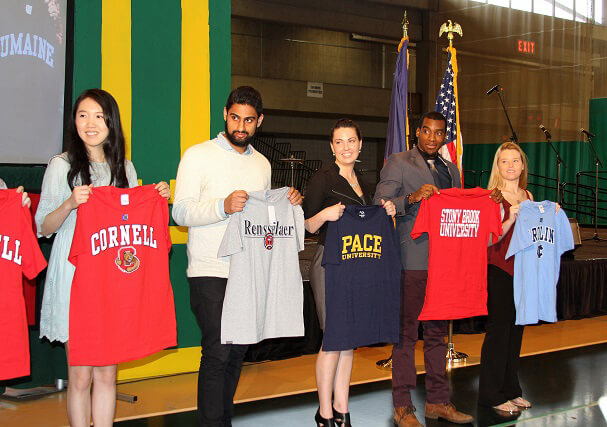 Students holding college t-shirts.